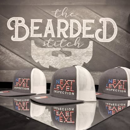 Custom embroidered M Inspection trucker hats displayed in front of a Bearded Stitch backdrop